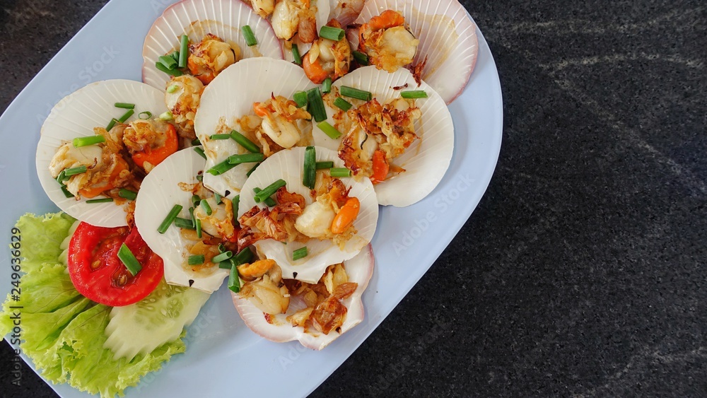 Grilled scallops shell with butter and garlic with cheese and spinach. Healthy food appetizer Baked parmesan scallops. Scallops grilled cheese delicious on the wooden table, Thai sea food. Grilled scallops shell with butter and garlic with cheese and spinach. Healthy food appetizer Baked parmesan scallops. Scallops grilled cheese delicious on the wooden table, Thai sea food.