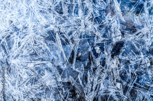 close up of dense ice crystal filled pond surface texture background on cold winter day