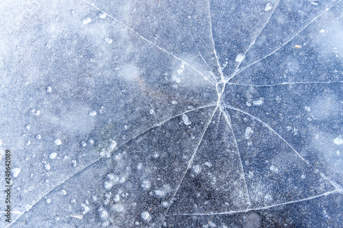 thin layer of ice on the pond surface with cracks texture background
