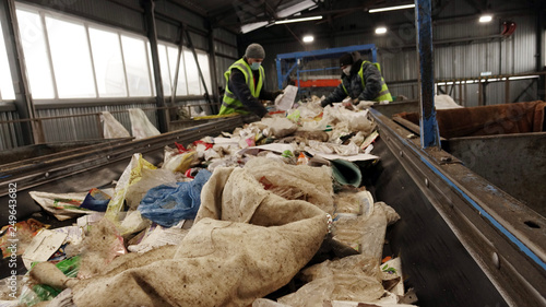 Workers at the waste processing plant. Sorting trash on a conveyor belt.