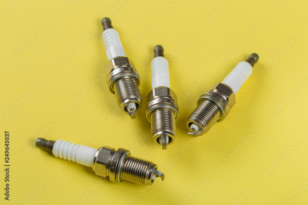 A set of new spark plugs a yellow background. A set of new spark plugs a yellow background.