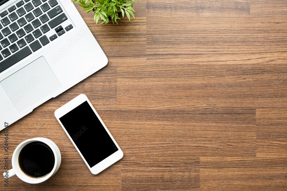 Wood office desk table with smartphone with blank screen, laptop and coffee cup. Top view with copy space, flat lay. Wood office desk table with smartphone with blank screen, laptop and coffee cup. Top view with copy space, flat lay.
