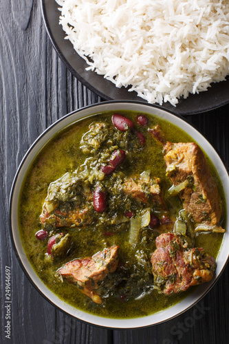 Persian national food meat stew with herbs and beans close-up in a bowl served with steam rice. Vertical top view photo