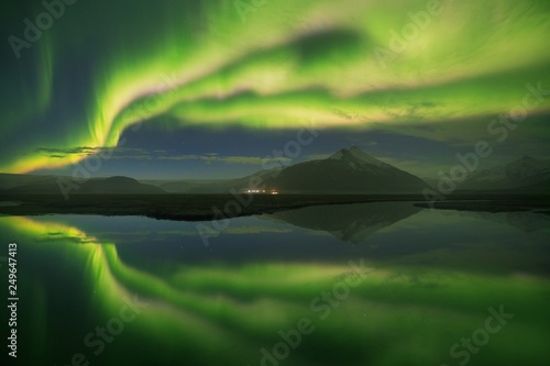 Aurora borealis above the sea and mountains. Jokulsarlon glacier lagoon, Iceland Green northern lights. Starry sky with polar lights Night winter landscape with aurora sea with sky reflection in water