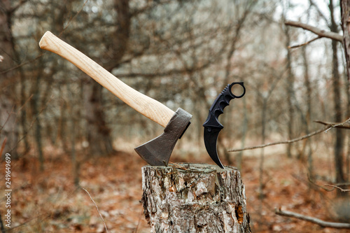 axe and karambit knife suck in the stump in the forest photo