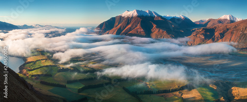 The valley is flooded in mist in a mountain environment. Over the fogs, only the high peaks of the mountains rise beneath the sunny sky. Misty morning on the Southern Island New Zealand, Christchurch