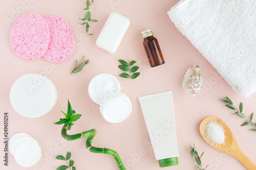 Flatlay of spa cosmetic with bamboo  salt for bath  cream and towel on pastel pink background  top view mock-up