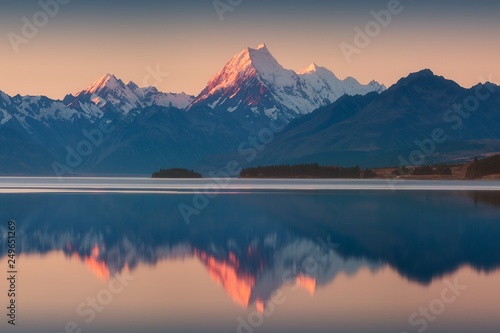 Snowy mountain range reflected in the still water of Lake Pukaki, Mount Cook, South Island, New Zealand. The turquoise water comes from Mt. Cook and Tasman glacier. Popular travel destination 