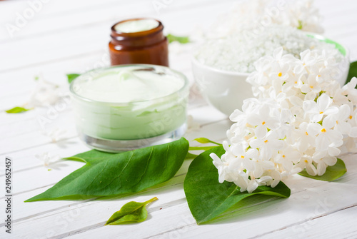 cosmetic creams and white lilac blossom on bright wooden table background