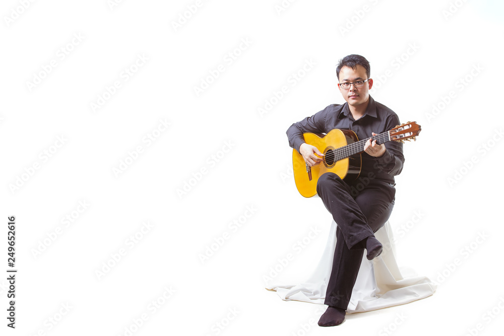 Portrait of asian man wearing playing guitar on white background looking to the guitar and copy space Portrait of asian man wearing playing guitar on white background looking to the guitar and copy space