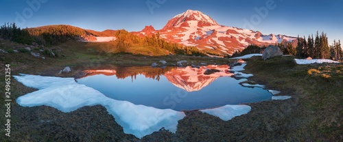 Fototapeta Naklejka Na Ścianę i Meble -  The beauty & tranquility of a summer evening at Mount Rainier National Park. Tall evergreen trees that line an alpine lake & blue sky are reflected on the calm water, Spray Park, Washington State, USA