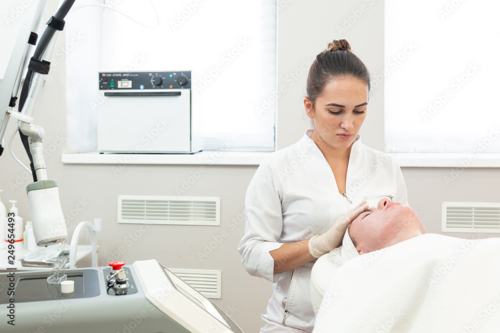 Laser rejuvenating facial face treatment at cosmetology clinic. Young woman getting lifting anti-aging and skincare, laser polishing facial therapy, aesthetic cosmetology. Laser rejuvenating facial face treatment at cosmetology clinic. Young woman getting lifting anti-aging and skincare, laser polishing facial therapy, aesthetic cosmetology.