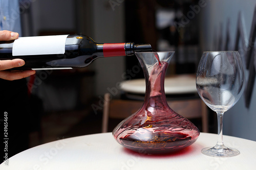 sommelier is pouring wine into a decanter photo