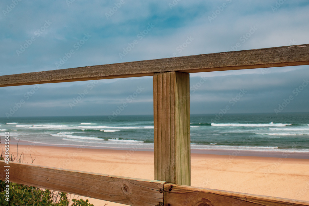 Wooden platform overlooking a wild south african beach; ocean waves and golden sand