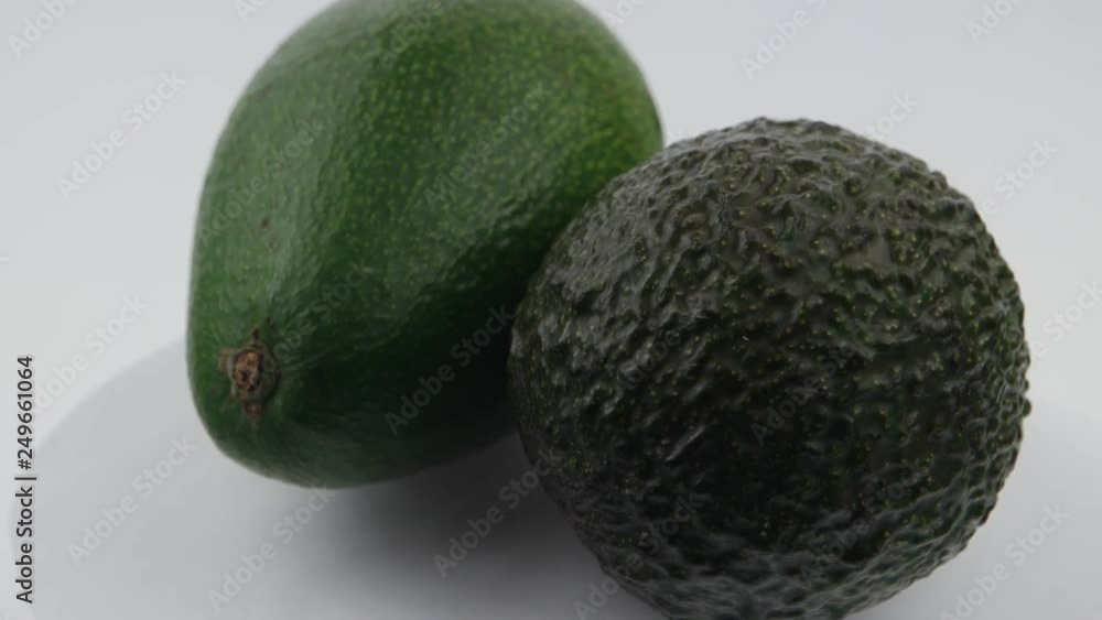 Two whole avocado are on a white surface, background Two whole avocado are on a white surface, background
