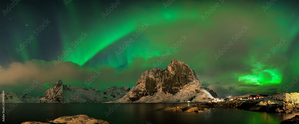 Aurora borealis dancing on mountain in fishing village at Reine and Sakrisoy, Lofoten, Norway Visiting the Lofoten Islands during winter time is a dream for all landscape photographers Christmas time