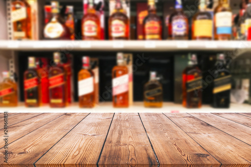 Wood table top and wine Liquor bottle on shelf blurred background