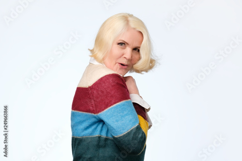 Senior european woman hides something in her hands and looks warily forward photo