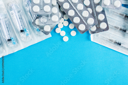 packs of white pills and syringes on a blue background