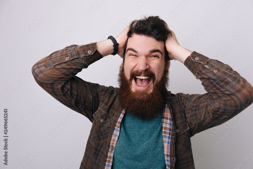 Handsomea excited bearded man is emotional and putting his hands on head Handsomea excited bearded man is emotional and putting his hands on head