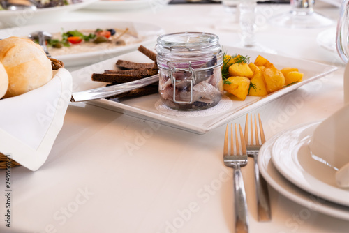Sealed jar with salted herring on the served holiday table with fried potatoes