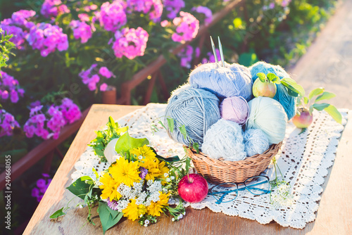 Women's hobby. Knitting and knitting needdles on the wood table in the garden on a Sunny summer day. photo