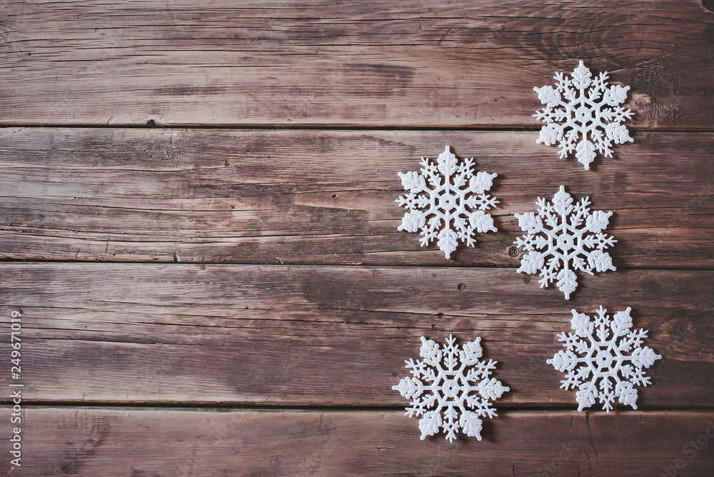 Fototapeta premium Christmas decor. White snowflakes and garland with glowing lamps on wooden background.