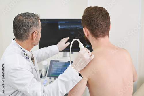 Man and doctor looking at screen, doing ultrasound check up photo