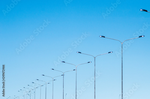 LED road lighting. Road lighting poles. A lot of road lanterns against the blue sky. Metal poles with lamps. Road construction.