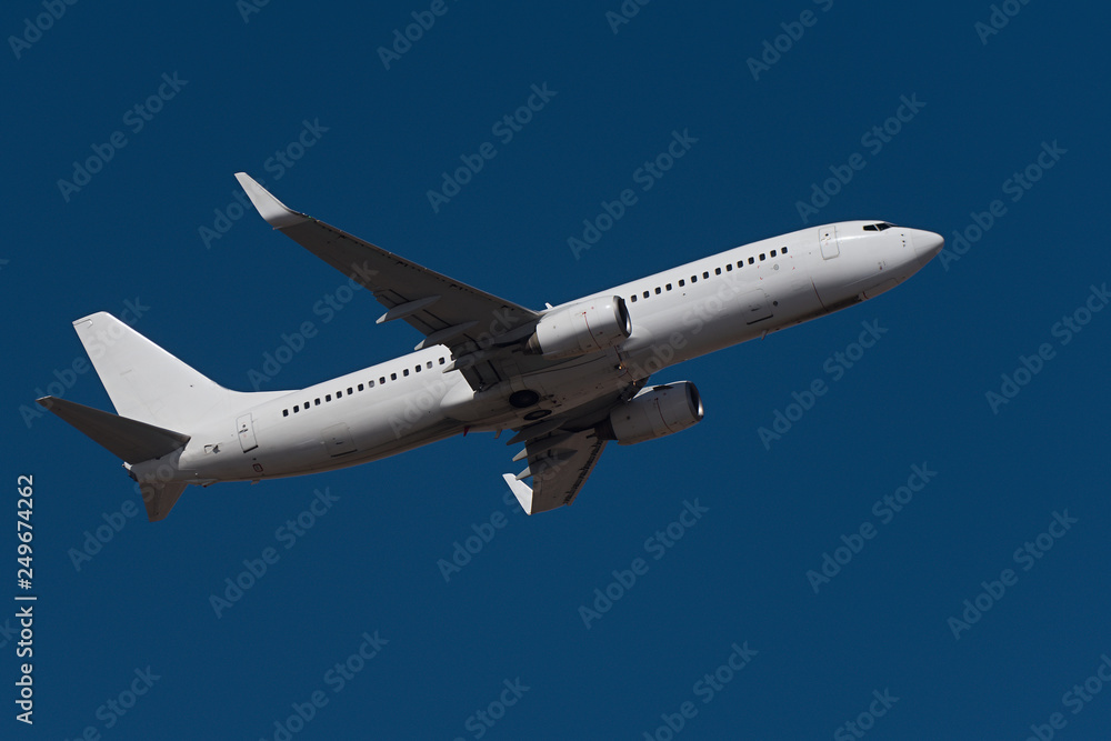 Fototapeta premium White flying airplane, travel background with airplane flying in the colorful blue sky