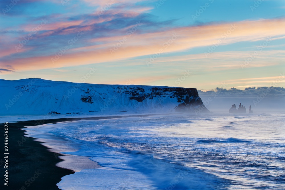 Reynisdrangar cliffs near the Vik town. Dramatic landscape with the Atlantic Ocean. Tourist attraction of Iceland. Rock formations on black Reynisfjara Beach at sunrise volcanic basalt sea stacks