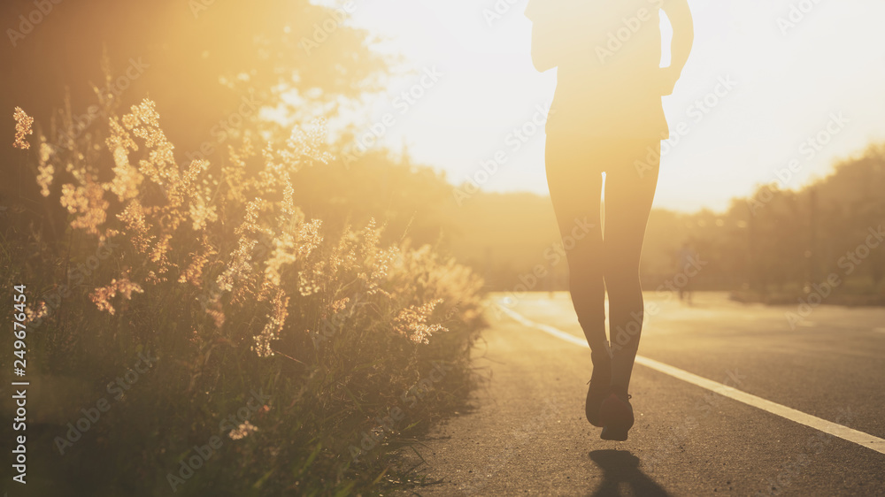Young fitness sport woman running on the road in the morning, Sun light flare
