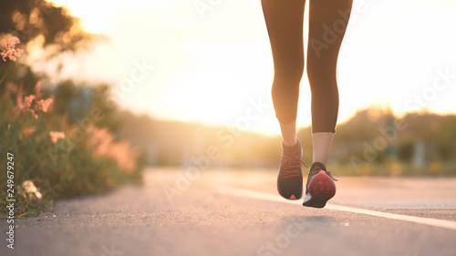 Young fitness sport woman running on the road in the morning  Sun light flare