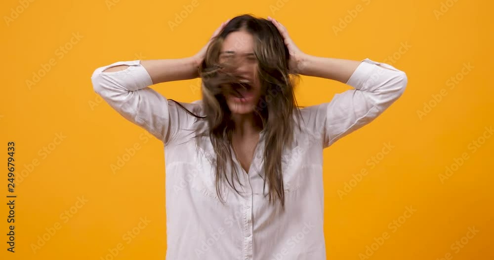 Crazy unhappy girl screaming and shaking her head on yellow background in studio Crazy unhappy girl screaming and shaking her head on yellow background in studio