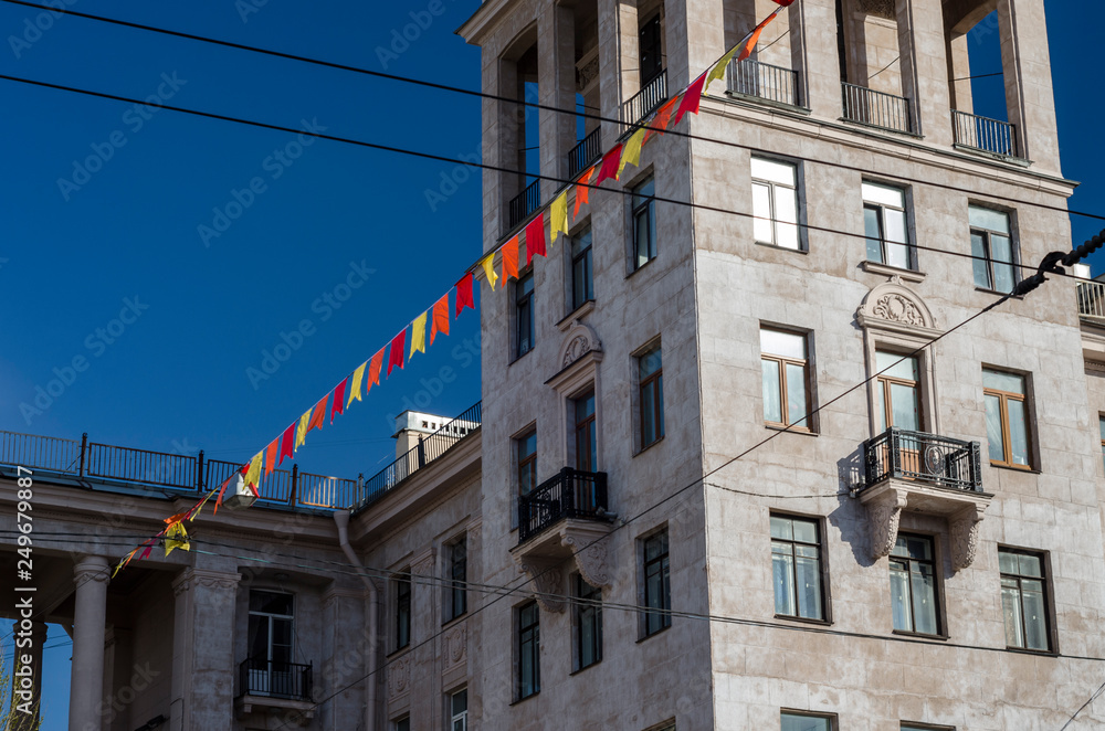 Decorative pommel buildings in the style of the Stalin Empire style and the facade of the building of natural stone. Festive colored flags. St. Petersburg. Russia, Narva Square, May 9, 2018 Decorative pommel buildings in the style of the Stalin Empire style and the facade of the building of natural stone. Festive colored flags. St. Petersburg. Russia, Narva Square, May 9, 2018