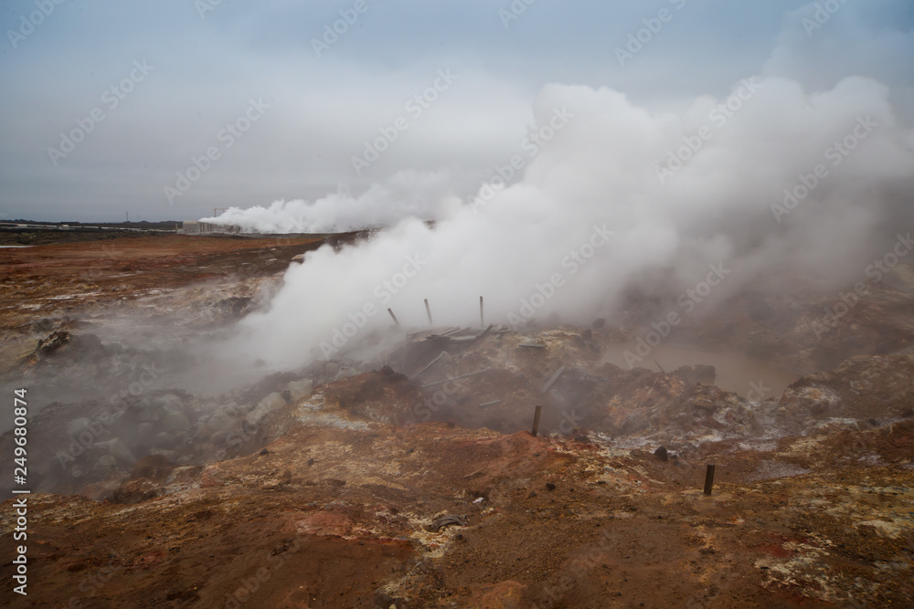 Desolate landscape of Iceland volcanic brown soil with steamy geyser mist
