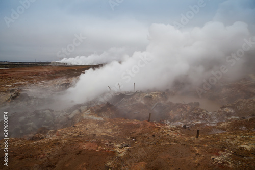 Desolate landscape of Iceland volcanic brown soil with steamy geyser mist