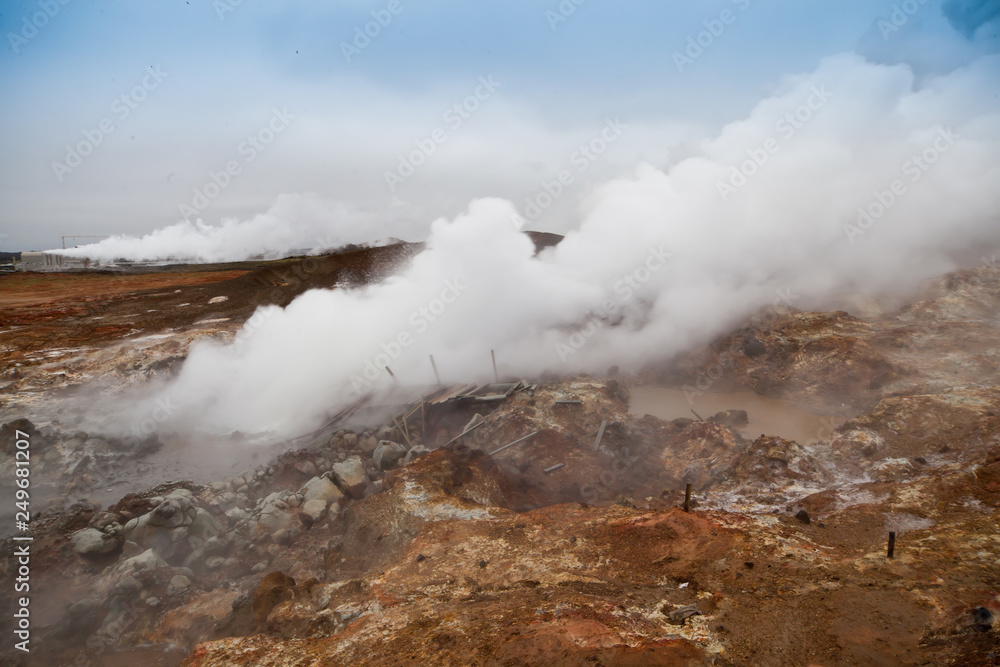Desolate landscape of Iceland volcanic brown soil with steamy geyser mist Desolate landscape of Iceland volcanic brown soil with steamy geyser mist