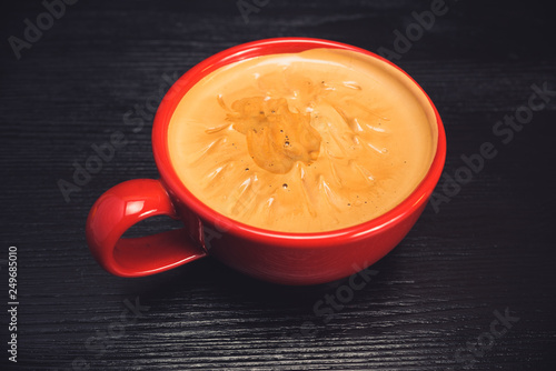 fresh aromatic coffee in a red mug on a black wooden background