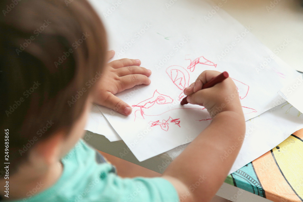 Toddler boy drawing in a table in the school. Top view. Toddler boy drawing in a table in the school. Top view.