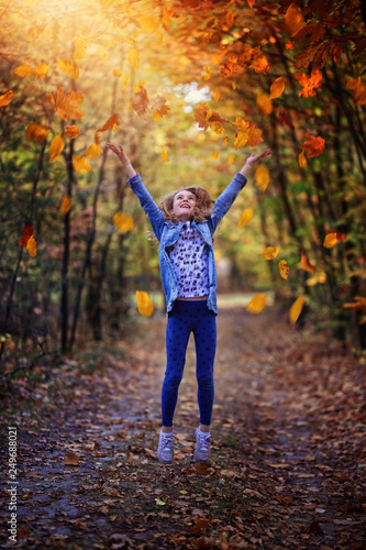 young girl tossing leaves on an autumn day