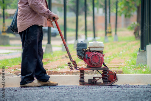 Man working the soil compactor on the paved floor