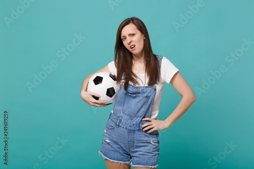 Disgusted disappointed young girl football fan support favorite team with soccer ball isolated on blue turquoise background. People emotions sport family leisure lifestyle concept. Mock up copy space. © ViDi Studio