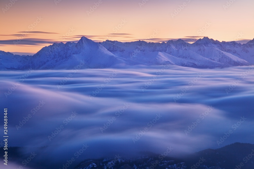 Panoramic view of beautiful winter wonderland mountain scenery in evening light at sunset. Carpathian mountains above the clouds. Christmas and New year. 