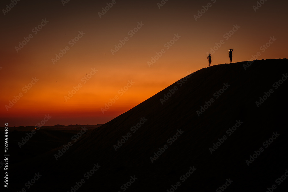 Photography session during sunset over a sand dune in Dubai desert. 
