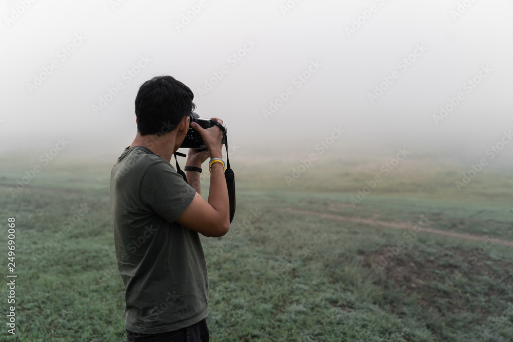 A man with a camera in the fog takes pictures