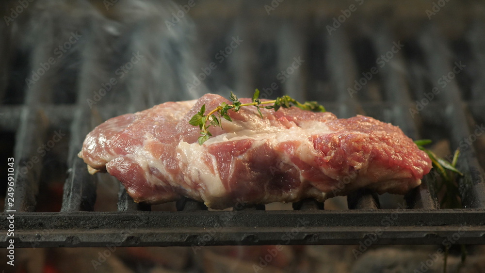 A juicy piece of choice beef, veal or lamb roasted on the grill with a haze and a twig of grilled wood in the kitchen of the restaurant, delicatessen, close-up video, slow-motion filming