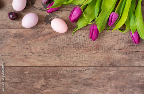 Easter eggs Pastel colored. Beautiful spring flowers - purple tulips on a wooden background. Floral frame with stunning flowers. Copy space