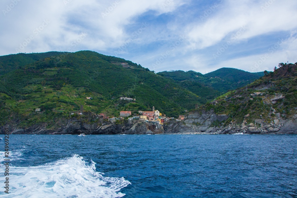 The town of Vernazza, one of the five small towns in the Cinque Terre national Park, Italy. View from the excursion ship. Amazing colorful small town located in the mountains near the sea.