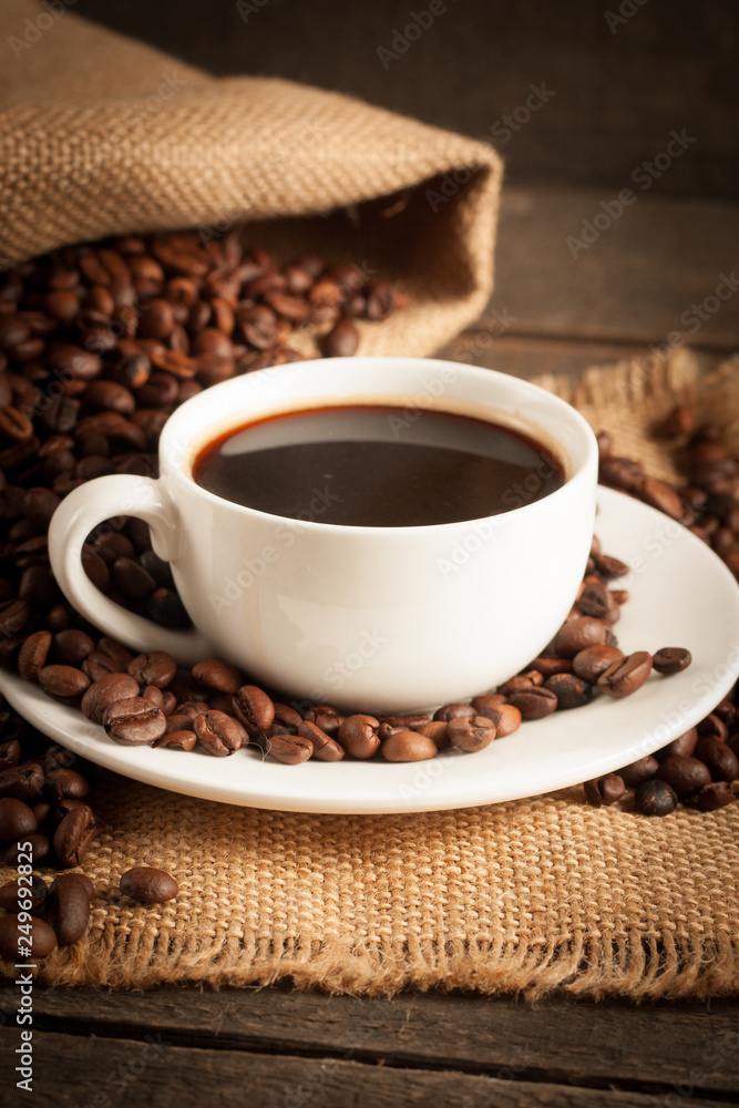 Coffee cup and beans on a rustic background. Coffee Espresso and a piece of cake with a curl. Cup of Coffee and coffee beans on table. Coffee cup and beans on a rustic background. Coffee Espresso and a piece of cake with a curl. Cup of Coffee and coffee beans on table.